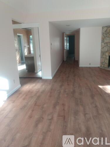 A room with wooden flooring and a wall with a stone patterned wallpaper.