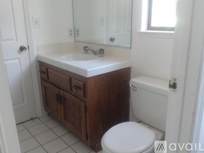 A bathroom with a white sink, wooden vanity, and a toilet.
