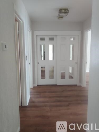 A hallway with a white door and wooden floors.