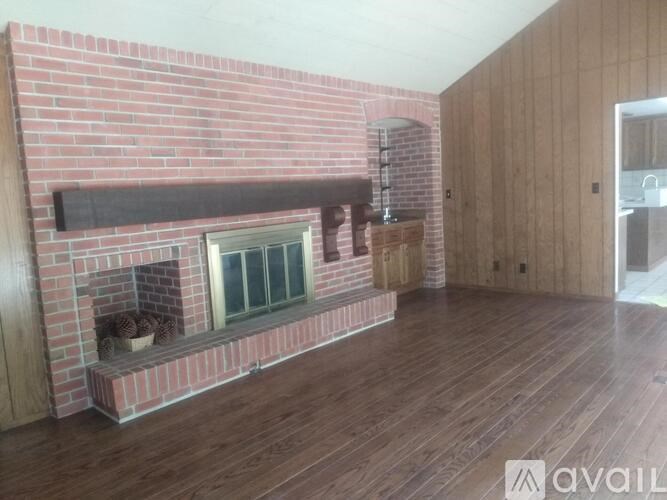 A room with a brick fireplace and wooden floors.