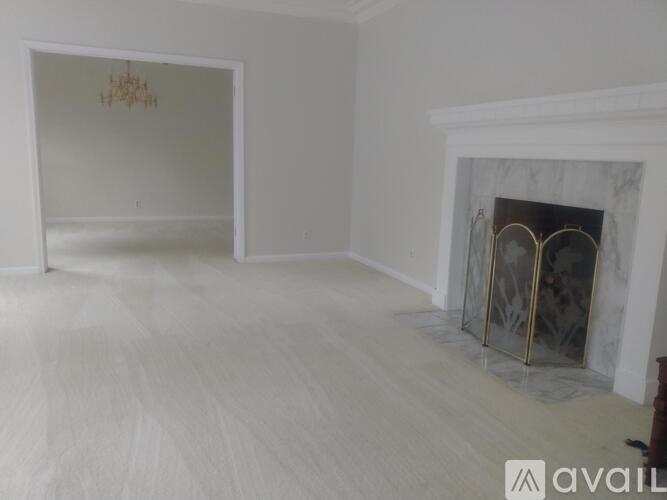 A large, empty room with a fireplace and a chandelier.