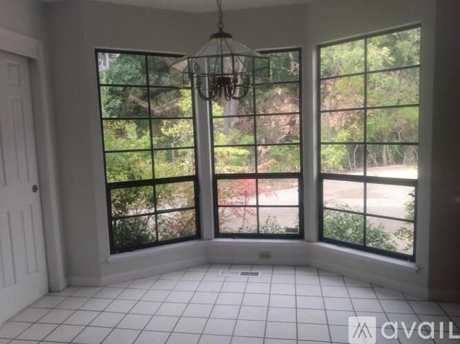 A room with a chandelier and large windows overlooking a garden.