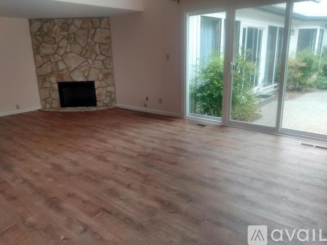A room with a stone fireplace and wooden flooring.