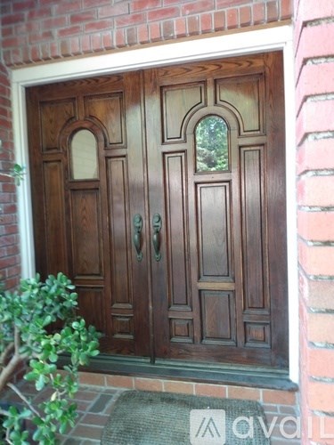 A wooden door with a glass window is set in a brick wall.