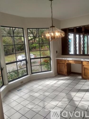 A room with a chandelier and a desk with a window overlooking a parking lot.
