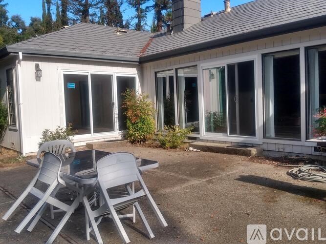 A patio with chairs and a table outside a house.