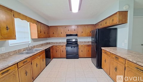 A kitchen with wooden cabinets and a black refrigerator.