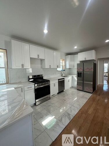 A kitchen with white cabinets and a marble countertop.