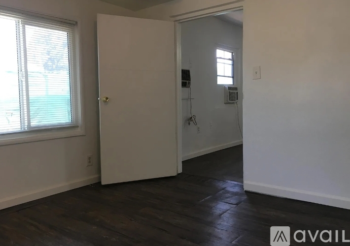 A room with wooden flooring and a staircase on the left side.