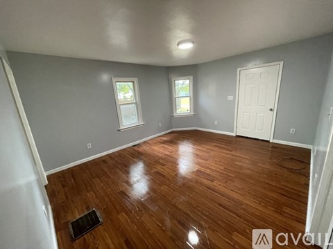 A room with wooden floors and two windows.