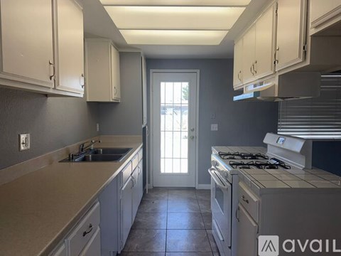 A kitchen with white cabinets and a stove top oven.