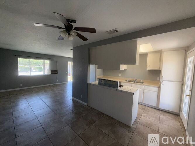 A spacious kitchen and living room with tile flooring and a ceiling fan.