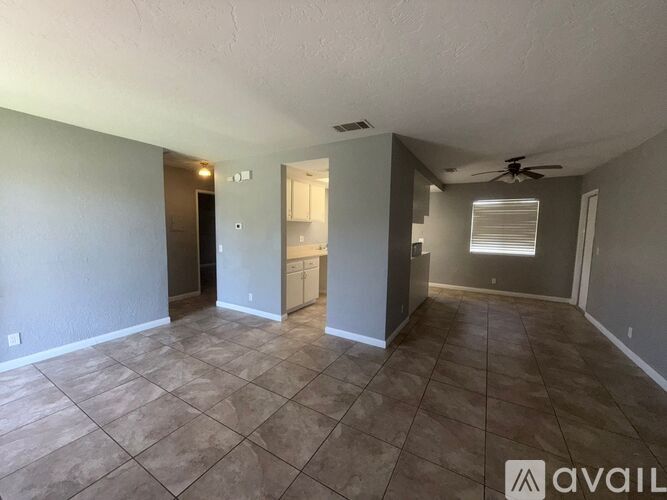 A spacious room with tile flooring and a ceiling fan.
