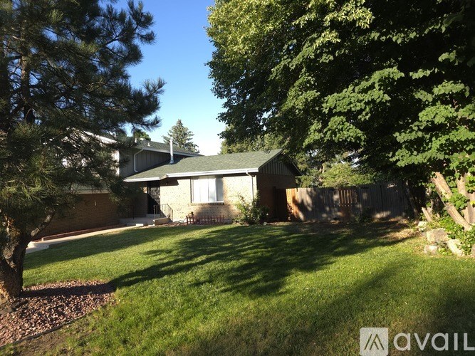 A house with a green lawn and trees in front.