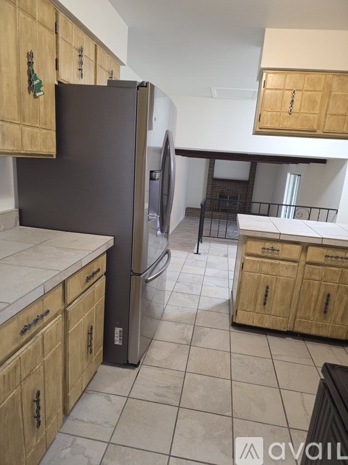 A kitchen with wooden cabinets and a black refrigerator.
