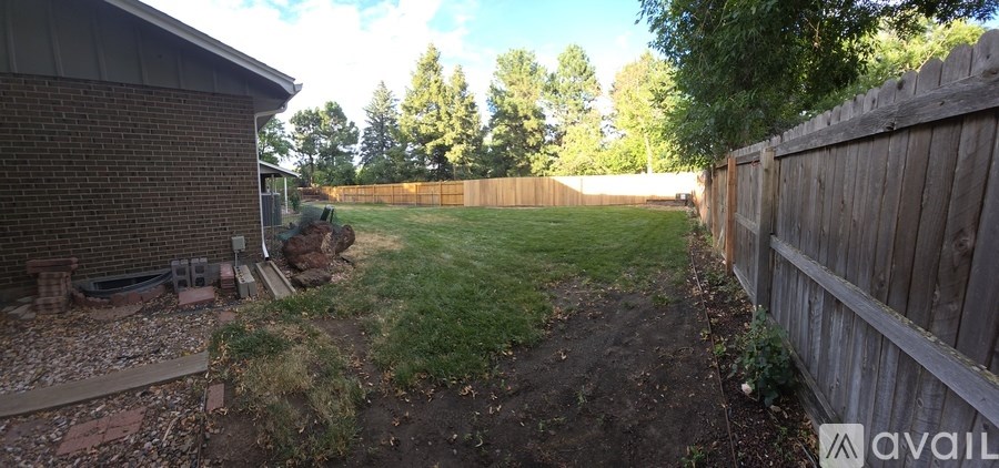 A backyard with a wooden fence and a grassy area.