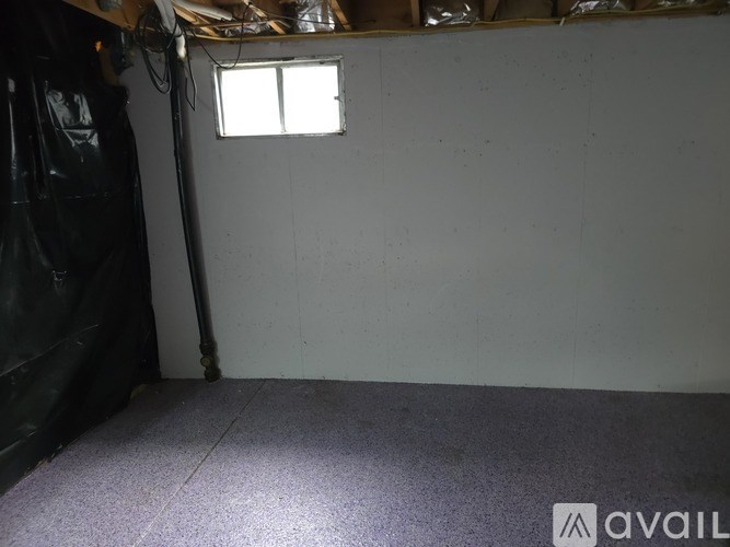 A room with a window and a pipe on the wall.