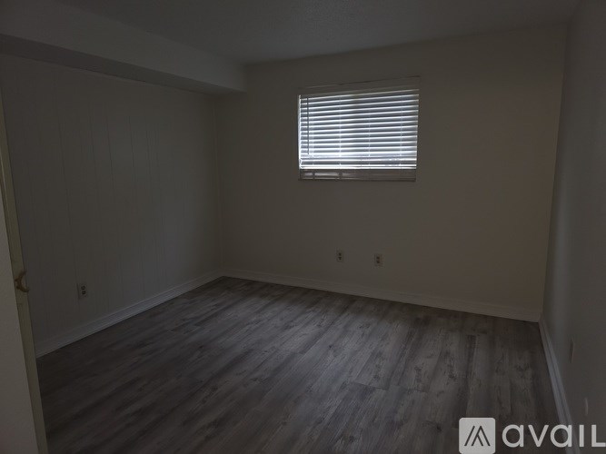 A room with wooden flooring and a window with blinds.