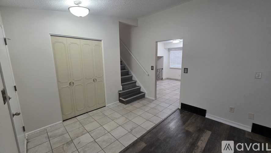 A spacious room with a staircase and a door.