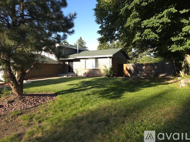 A house with a green lawn and trees in front.