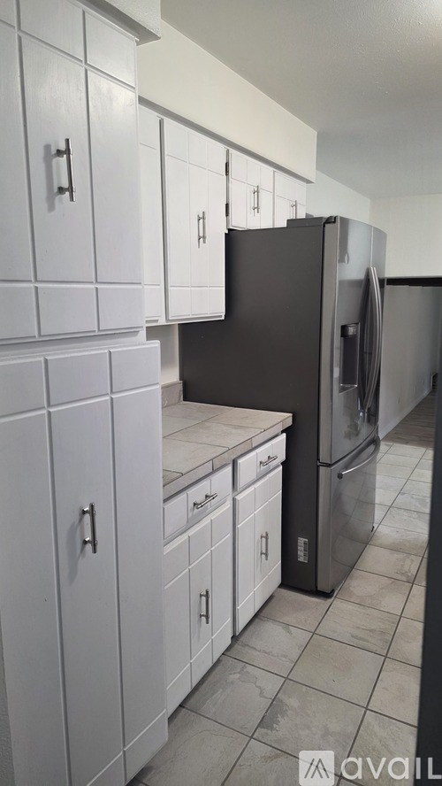 A kitchen with white cabinets and a black refrigerator.