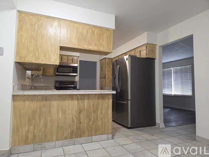 A kitchen with wooden cabinets and a black refrigerator.