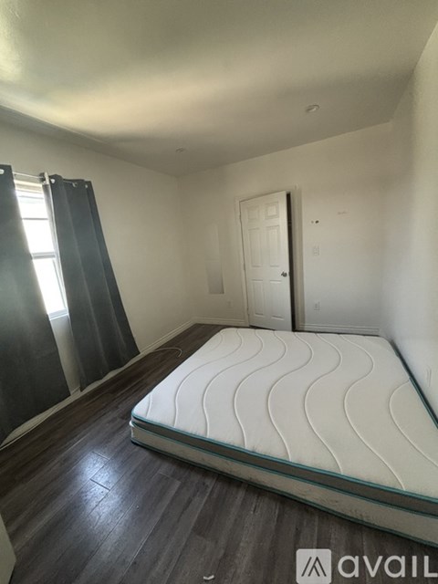 A bedroom with a mattress on a wooden floor.