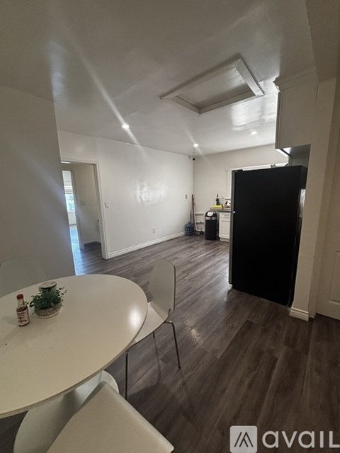 A kitchen with a table and chairs in the foreground and a black refrigerator in the background.