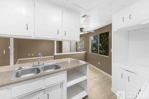 A kitchen with white cabinets and a sink.