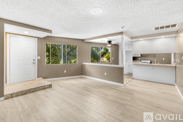 A spacious room with a white door and a window overlooking trees.