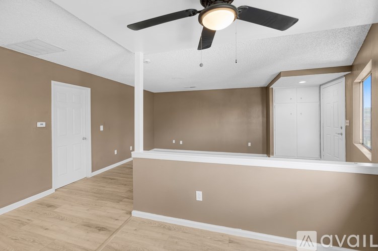 A room with a ceiling fan and light fixture, and a wall with a window.