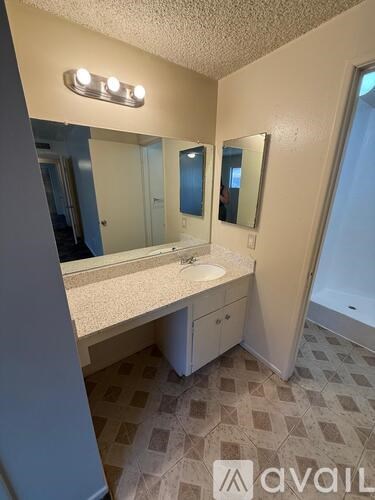 A bathroom with a sink, mirror, and tiled floor.