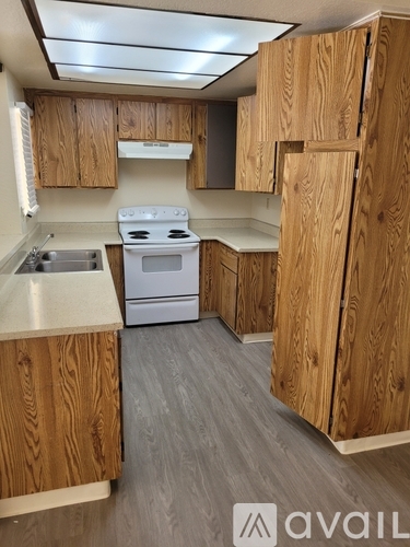 A kitchen with wooden cabinets and a white stove top oven.