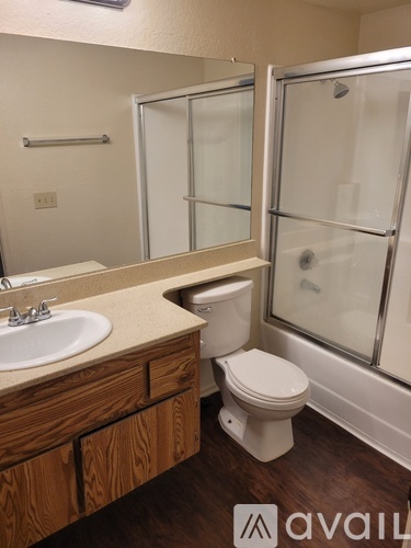 A bathroom with a toilet, sink, mirror, and shower.