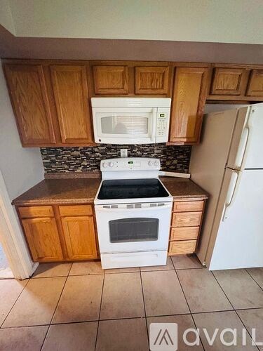 A kitchen with wooden cabinets and a white microwave above the stove.