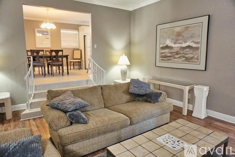A living room with a couch, a coffee table, and a painting on the wall.