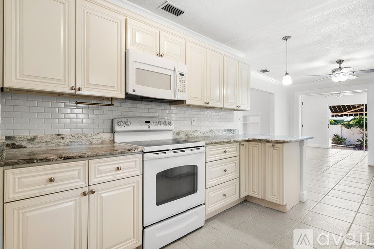 A living room with a couch, chair, and a painting of a palm tree.