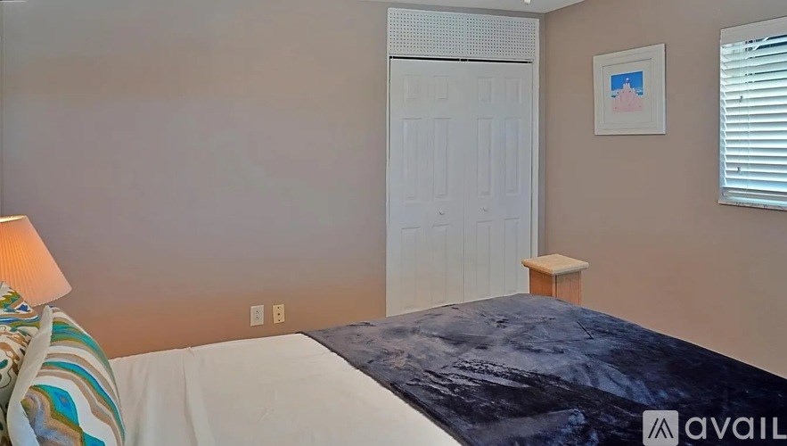 A bedroom with a bed, a lamp, and a picture on the wall.