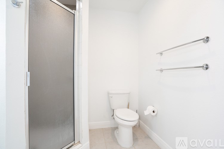 A white toilet sits in a bathroom next to a glass shower door.