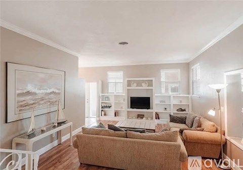 A living room with a couch, a television, and a painting of a beach scene on the wall.
