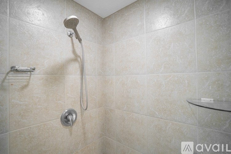 A shower with a silver shower head and a silver hand held shower head.