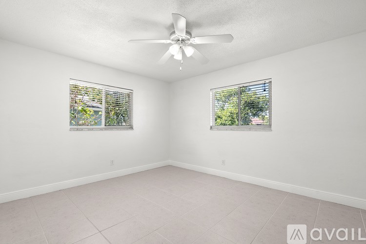 A room with a ceiling fan and two windows.