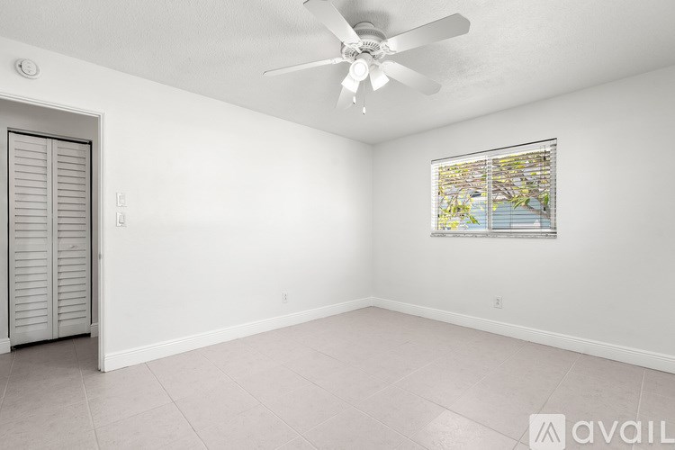 A room with a ceiling fan and a window with blinds.