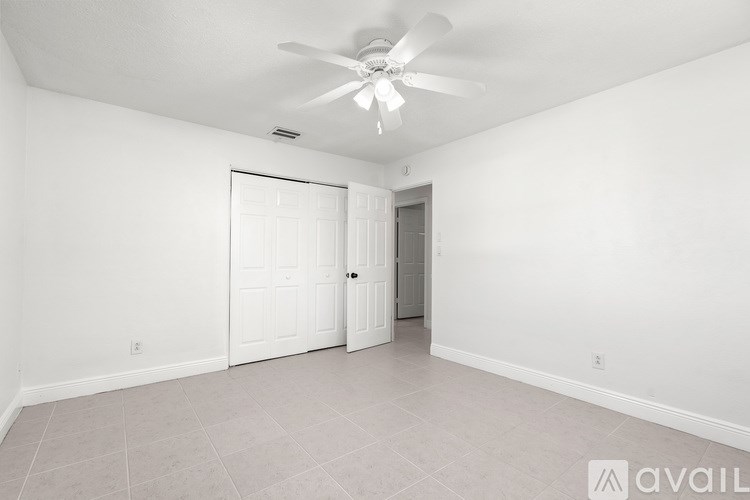 A room with a ceiling fan and two doors.