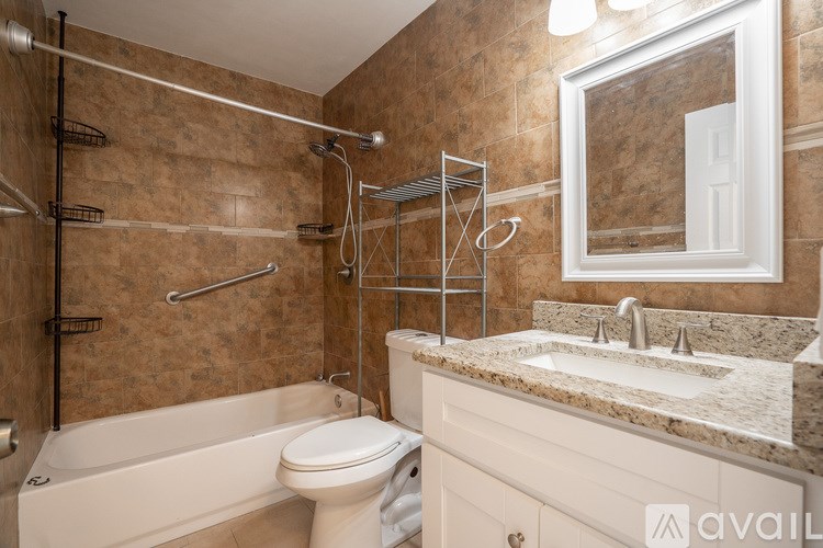 A bathroom with a brown tiled wall and a white toilet.