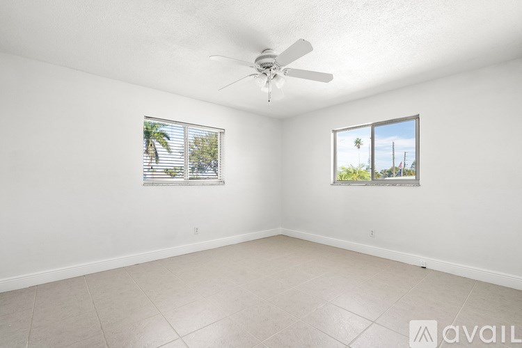 A room with a ceiling fan and two windows.