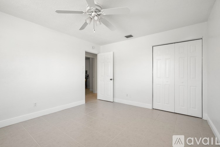 A spacious room with a ceiling fan and two doors.