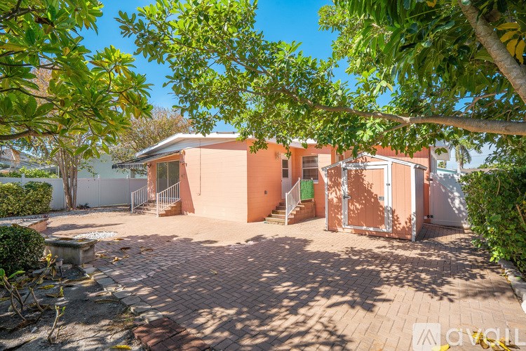 A backyard with a brick patio and a tree in the foreground.