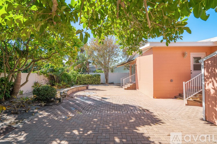 A house with a peach-colored exterior is surrounded by greenery and has a driveway leading to the garage.