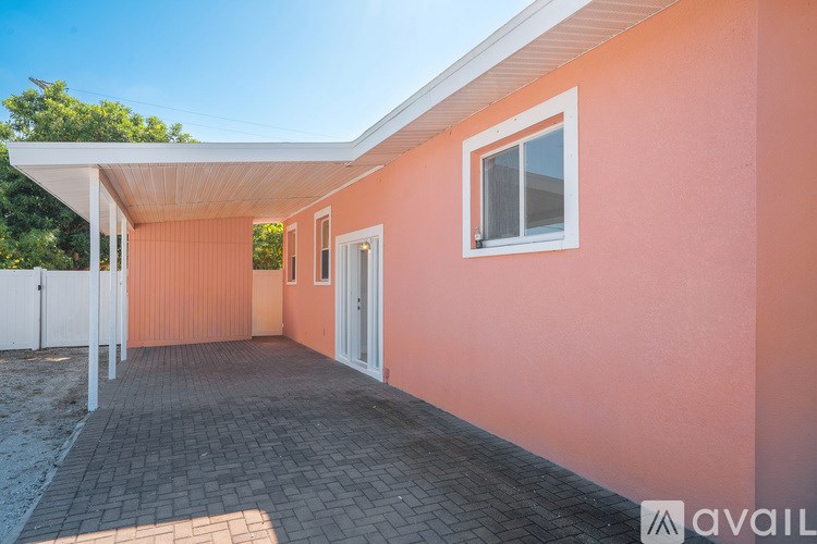 A house with a white roof and a pink wall with a window and a door.
